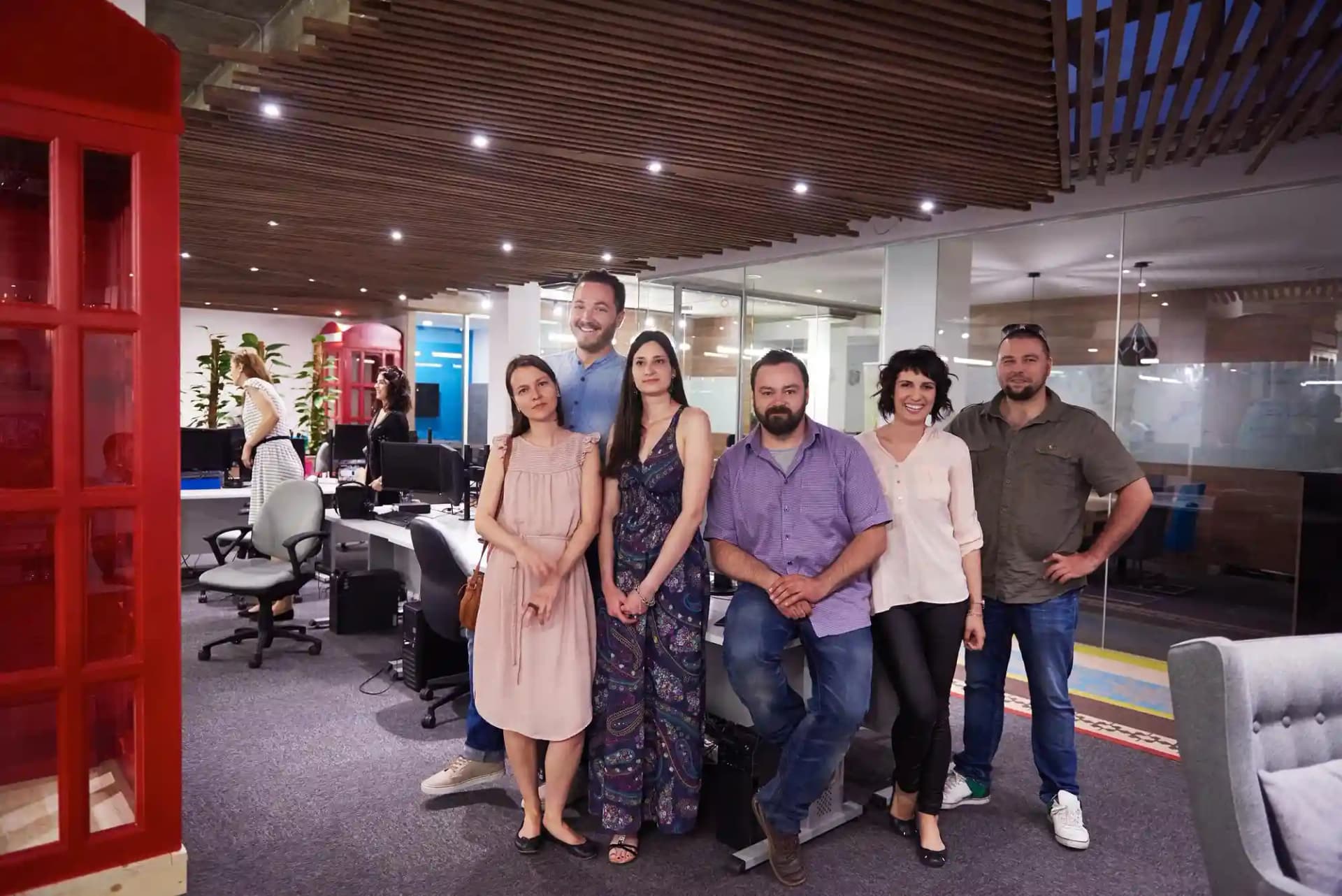 A group of Rankupper professionals stands together in front of a classic phone booth, smiling and engaged in conversation.