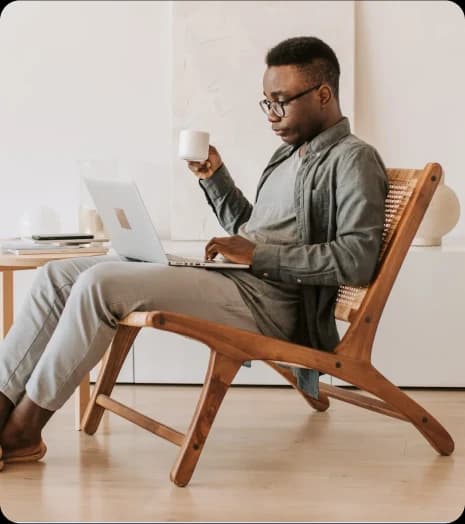 A man sits in a chair with a laptop and coffee, illustrating the theme of overcoming limitations in career opportunities.