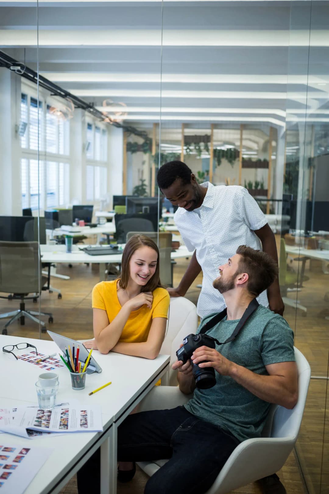 Three team members engaged in discussion around a table in an office setting at Rankupper.