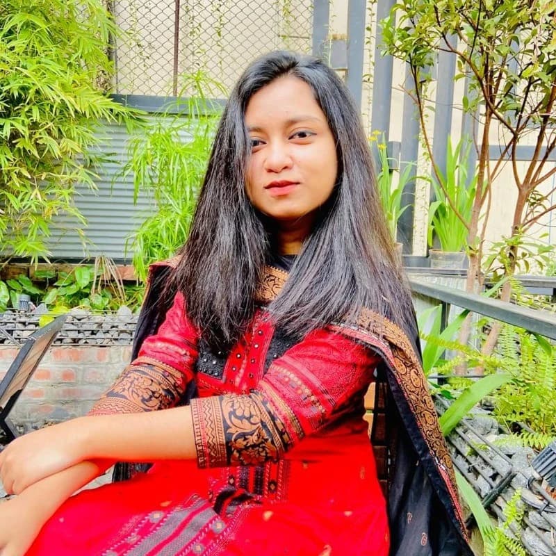 A woman in a blue shirt stands with arms crossed, representing Tayaba Amin, Business Development Executive at Rankupper.
